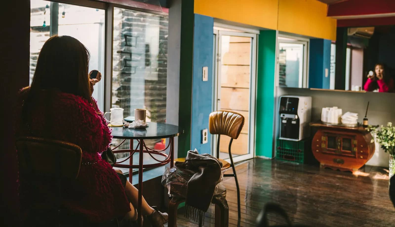 Person seated by the window of a colorful cafe in Ikseon-dong, Seoul