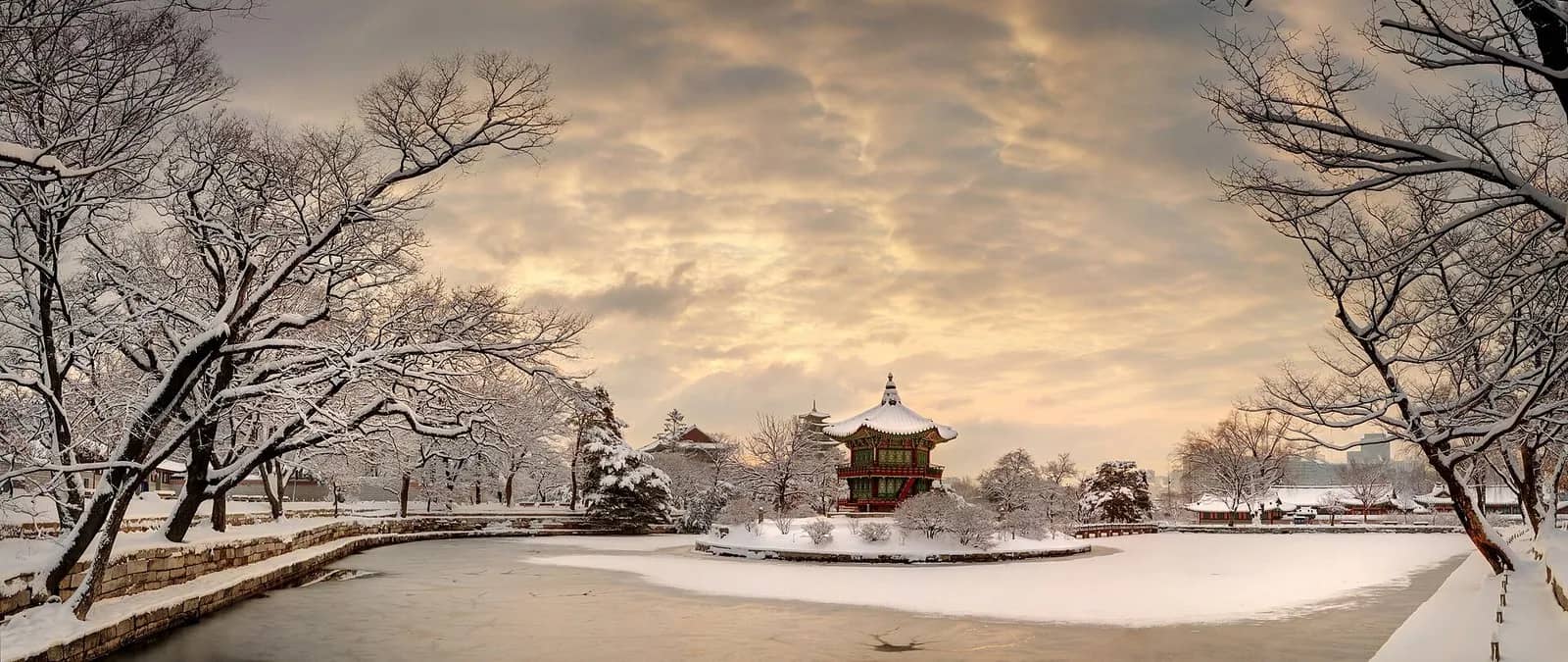 夜明けの景福宮で、雪に覆われた香遠亭と凍った池