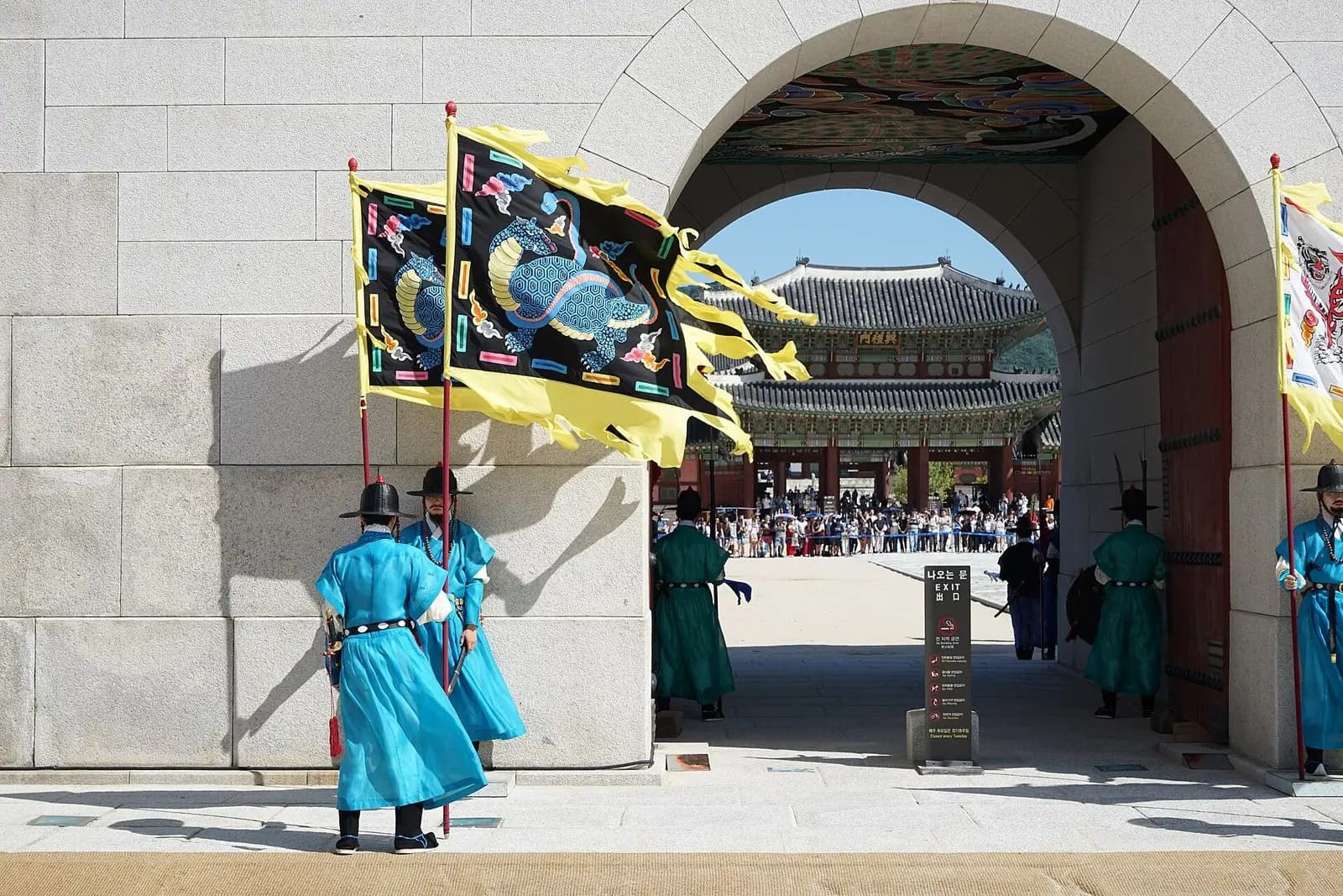Costumed royal guards with flags at a Gyeongbokgung gate with the palace hall beyond