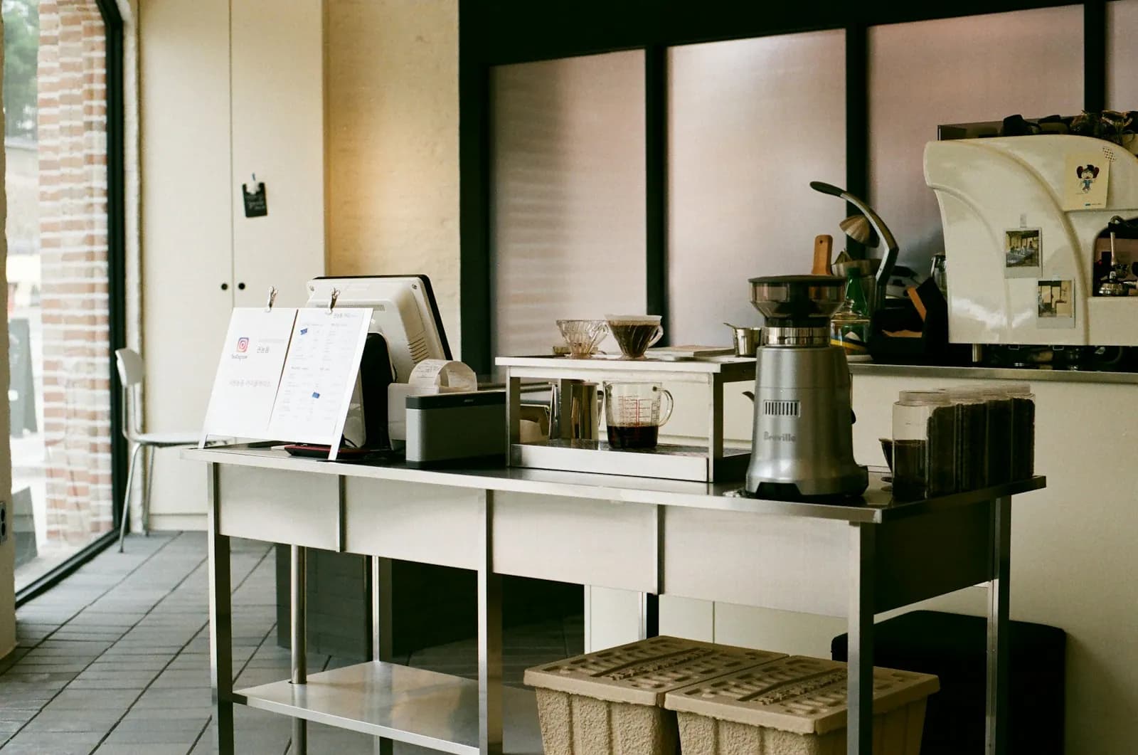 Steel cafe counter with pour-over coffee equipment beside a window in Seoul
