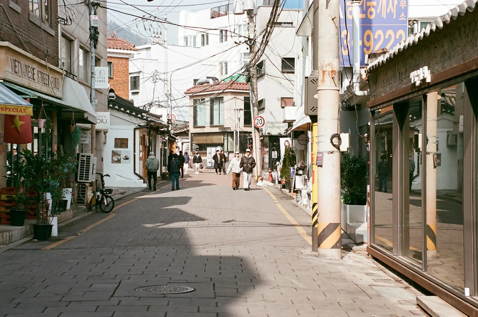 ソウルの西村で、小さな店が並ぶ狭い通りを歩く人々
