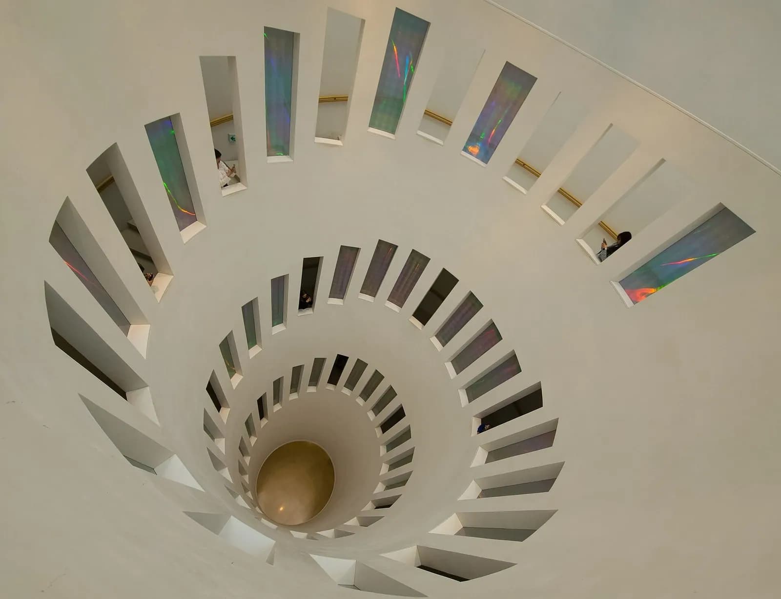 White spiral staircase with iridescent glass windows seen from above inside the Leeum museum