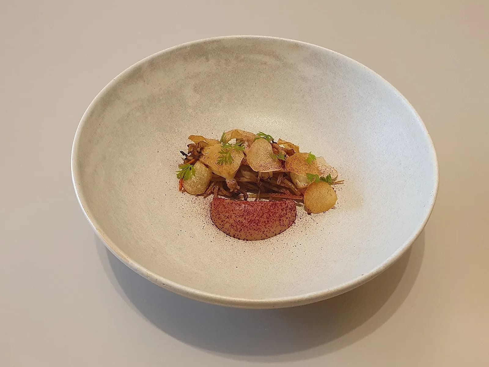 Small plated mushroom japchae in a pale ceramic bowl at a modern Korean restaurant in Hannam-dong