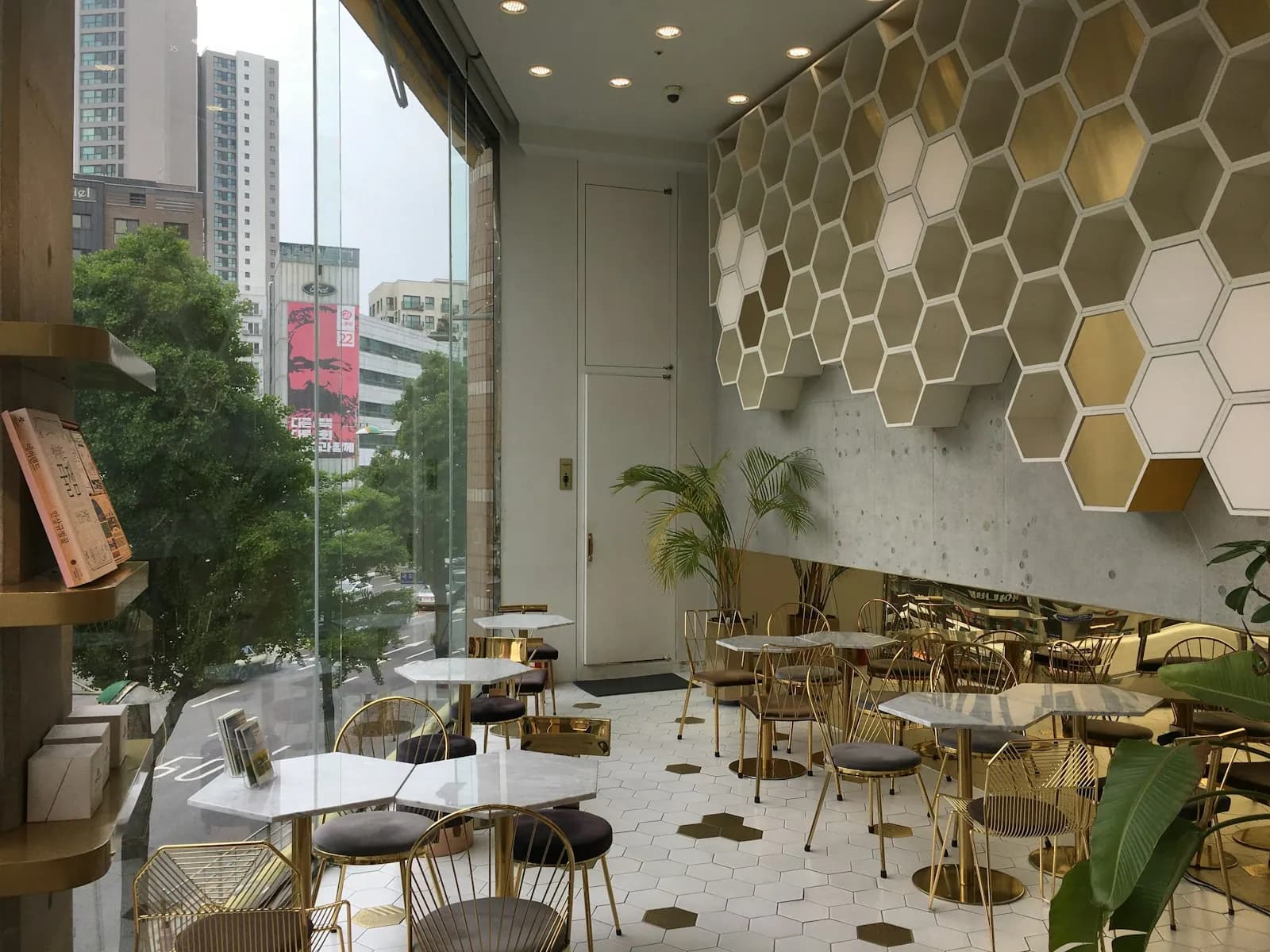 Bright Seoul cafe interior with small tables, gold chairs and floor-to-ceiling windows