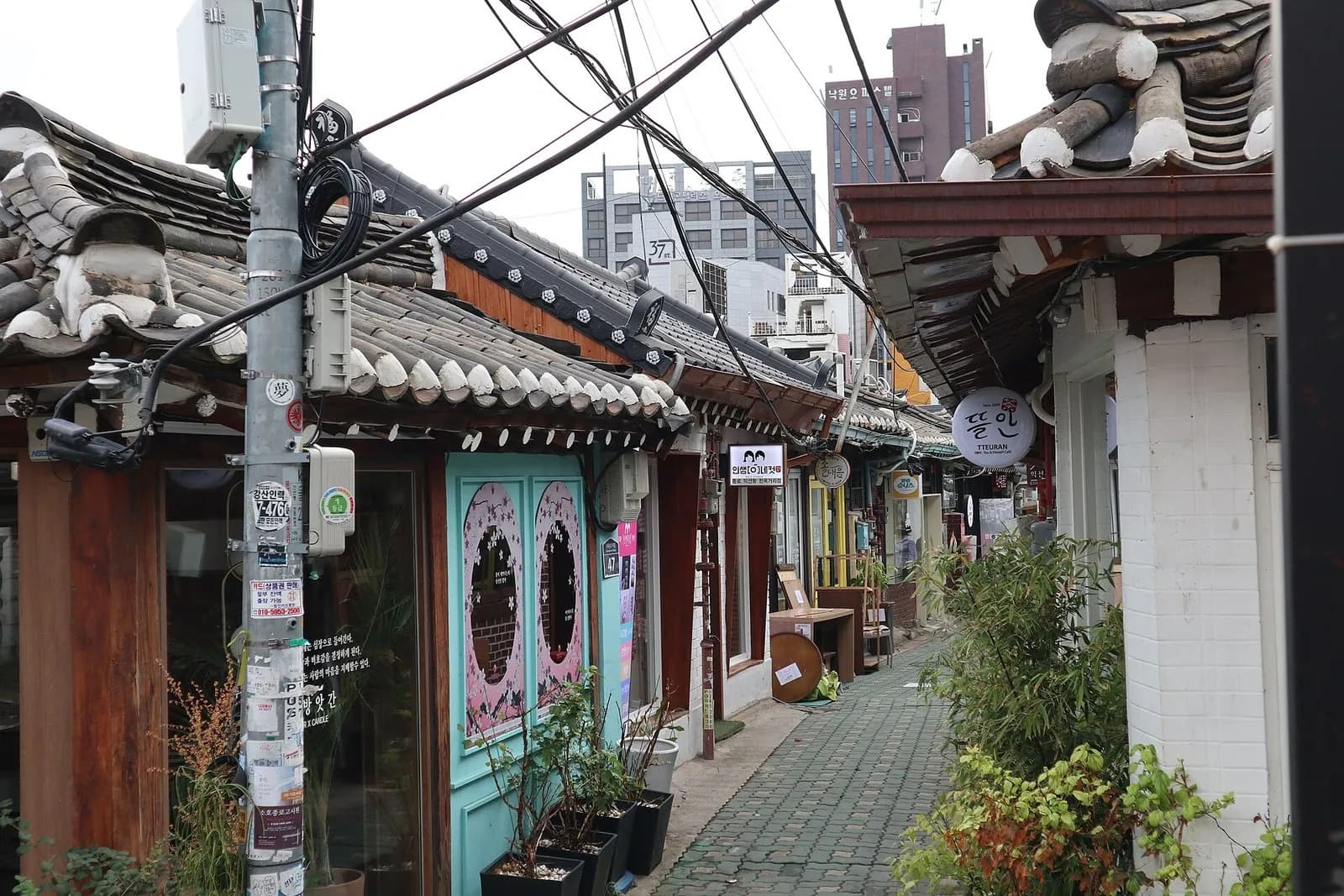 Narrow Ikseon-dong alley lined with low hanok houses, tiled roofs and small shop signs