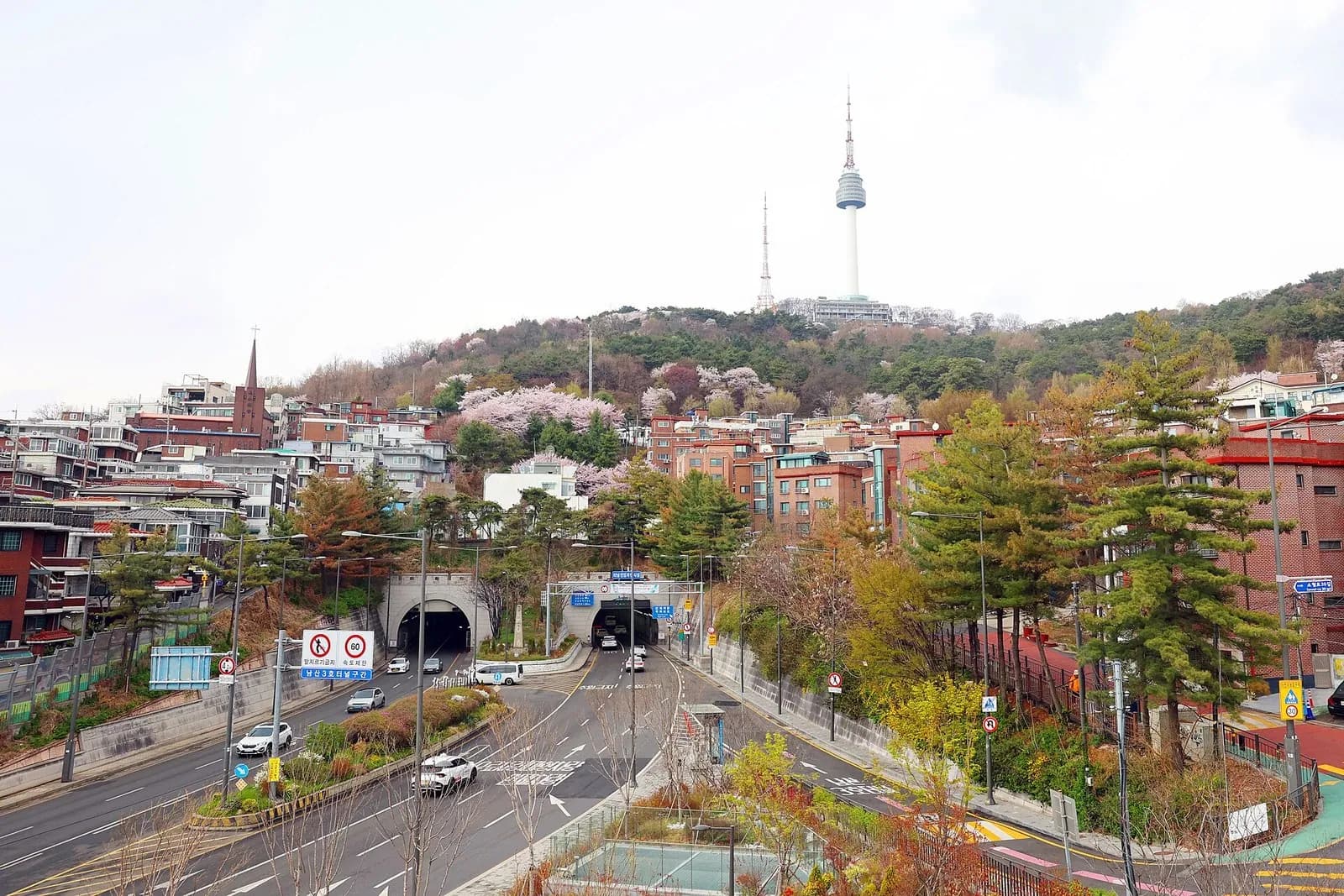 Haebangchon hillside houses below Namsan and N Seoul Tower, with a road tunnel in front