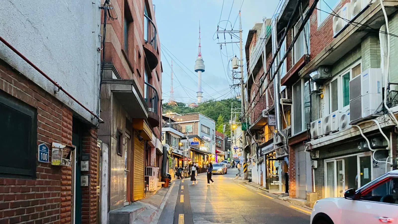 Narrow Seoul side street of low brick buildings with N Seoul Tower on the hill above