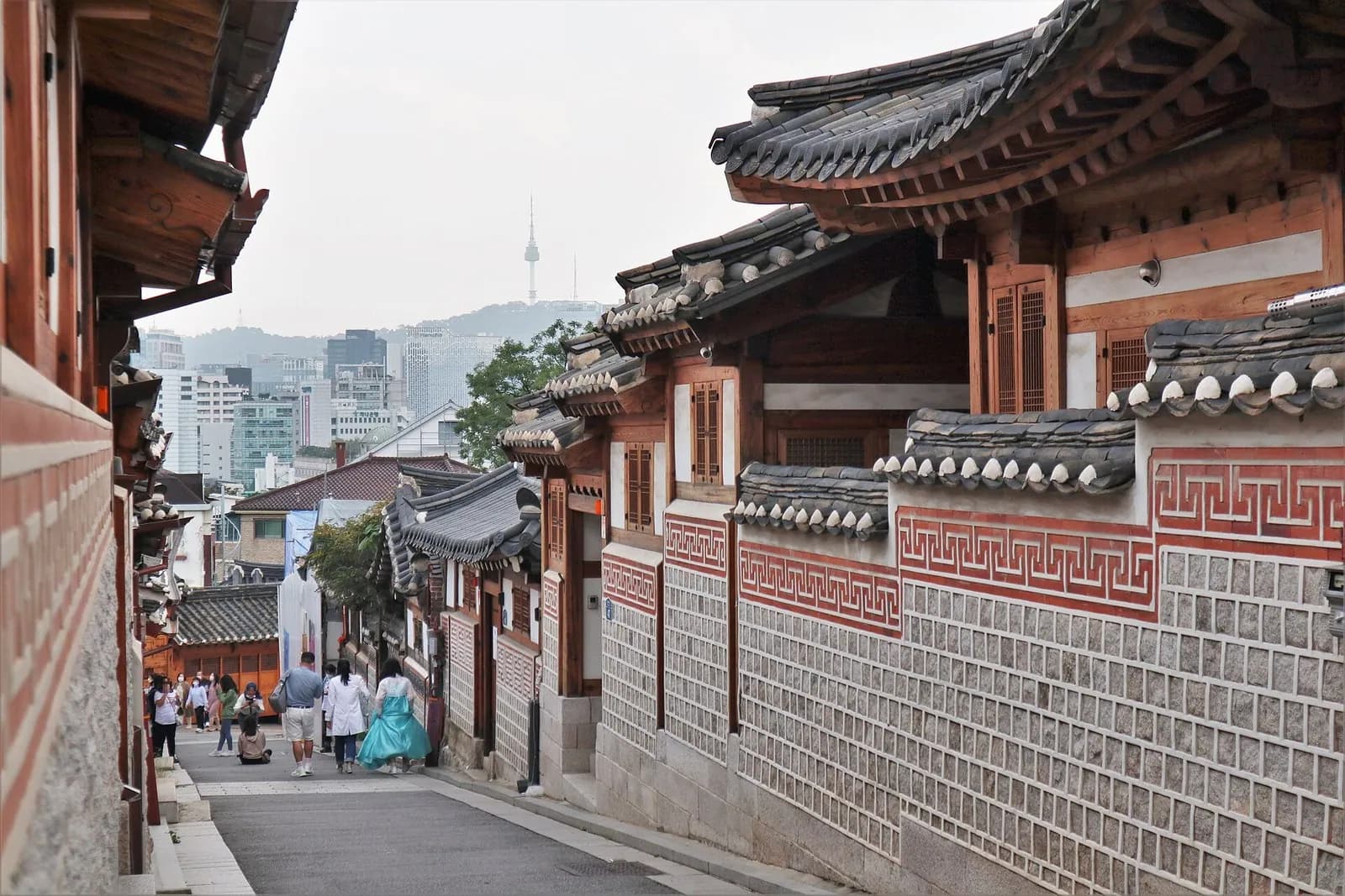 Bukchon Hanok Village lane with tiled roofs, patterned walls and N Seoul Tower beyond