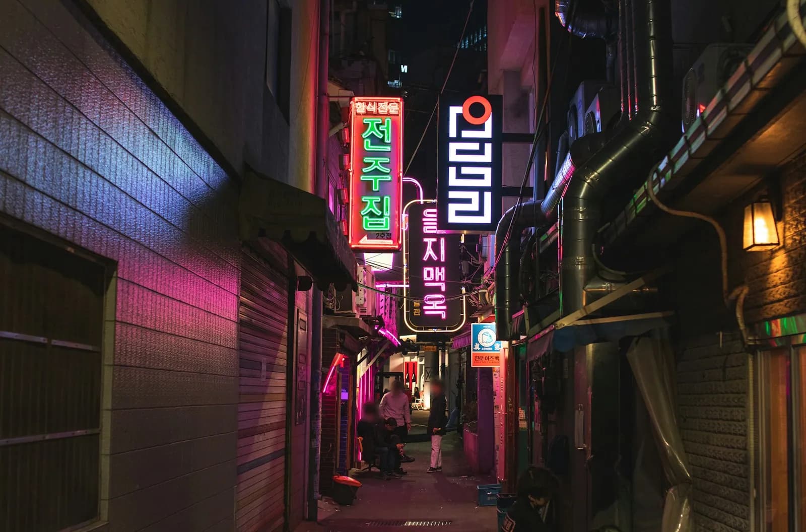 Narrow Seoul alley at night lit by pink and green neon signs
