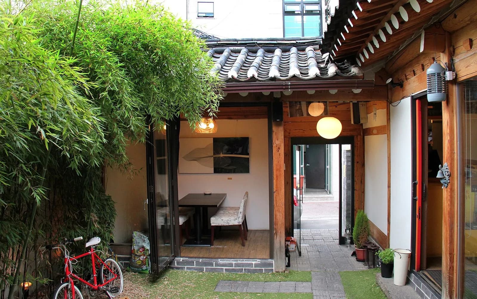 Courtyard of a hanok cafe in Tongui-dong, Seoul, with bamboo, a red bicycle and a tiled roof