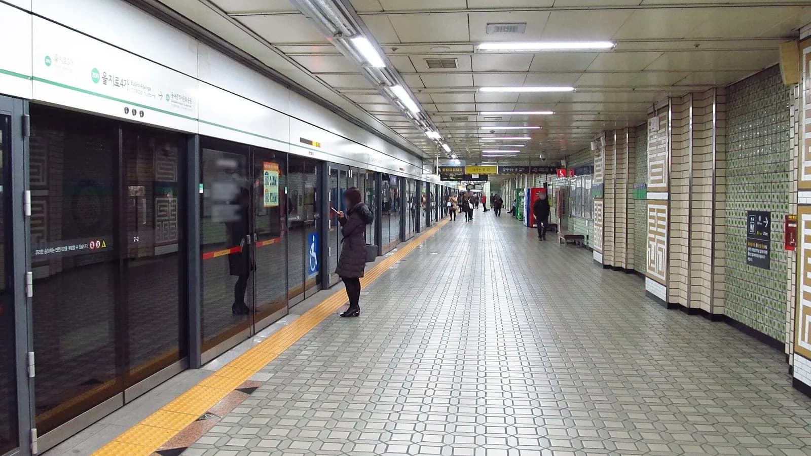 ホームドアのあるソウル地下鉄2号線乙支路4街駅のホームと、電車を待つ数人の乗客