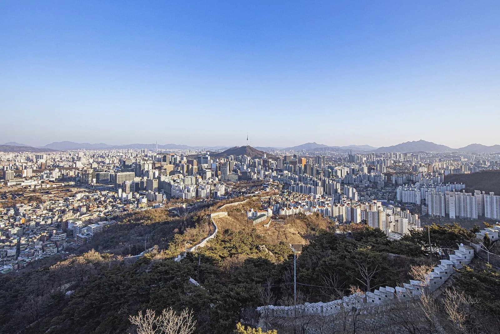 沿著仁王山蜿蜒而下的首爾城郭，遠處是首爾市中心與南山