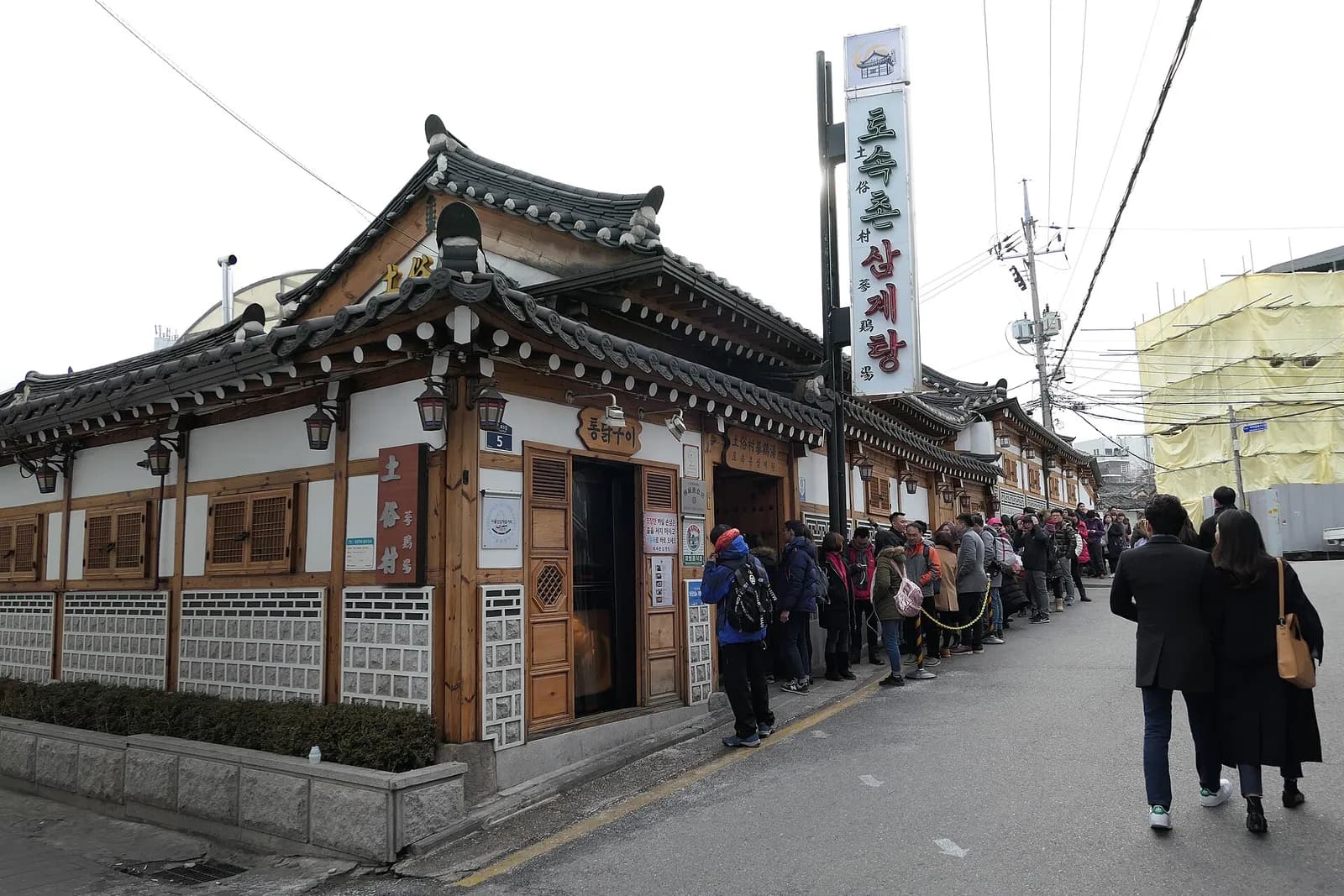 Hanok-style samgyetang restaurant in Jongno-gu, Seoul, with customers lining up along the outer wall
