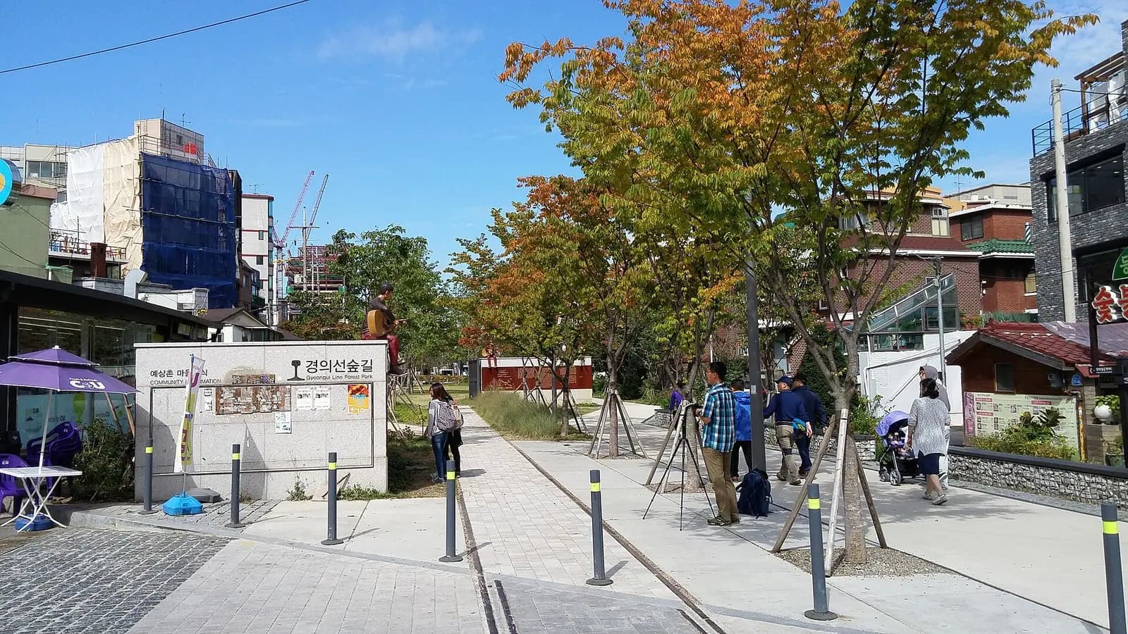 Gyeongui Line Forest Park path with old railway rails set in the paving, autumn trees