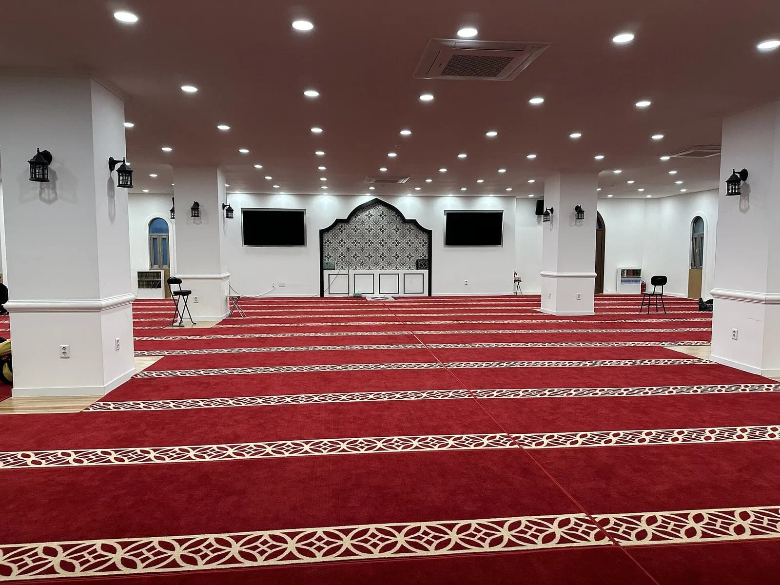 Prayer hall of Seoul Central Mosque with red patterned carpet, white columns and mihrab