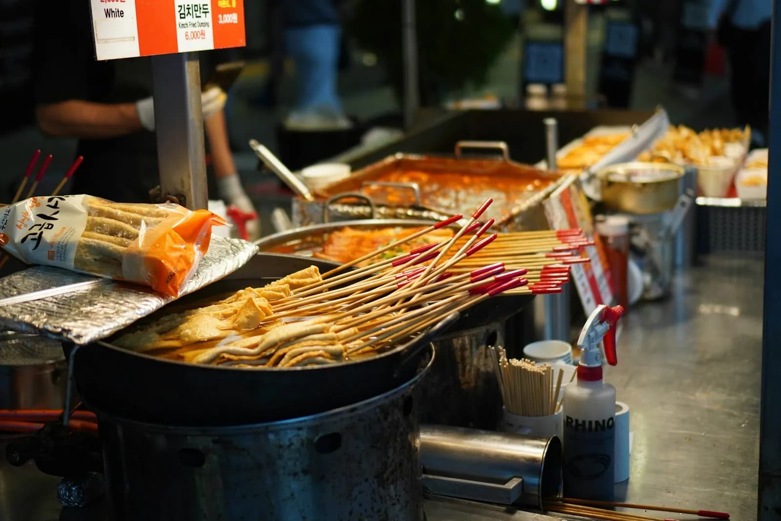 Fish cake skewers simmering in a metal pot at a Myeongdong night market stall
