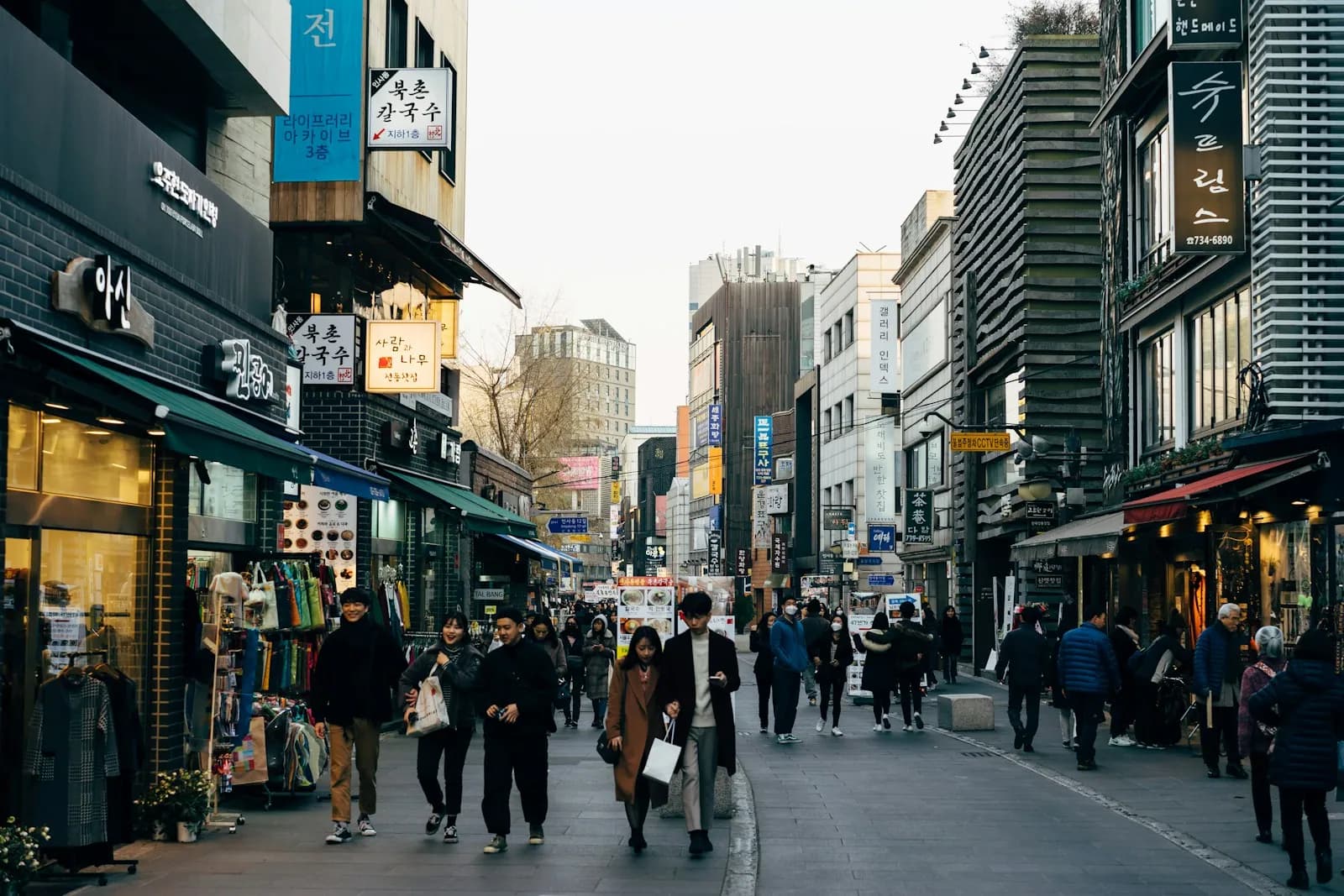 People walking along a Seoul shopping street of storefronts in daytime