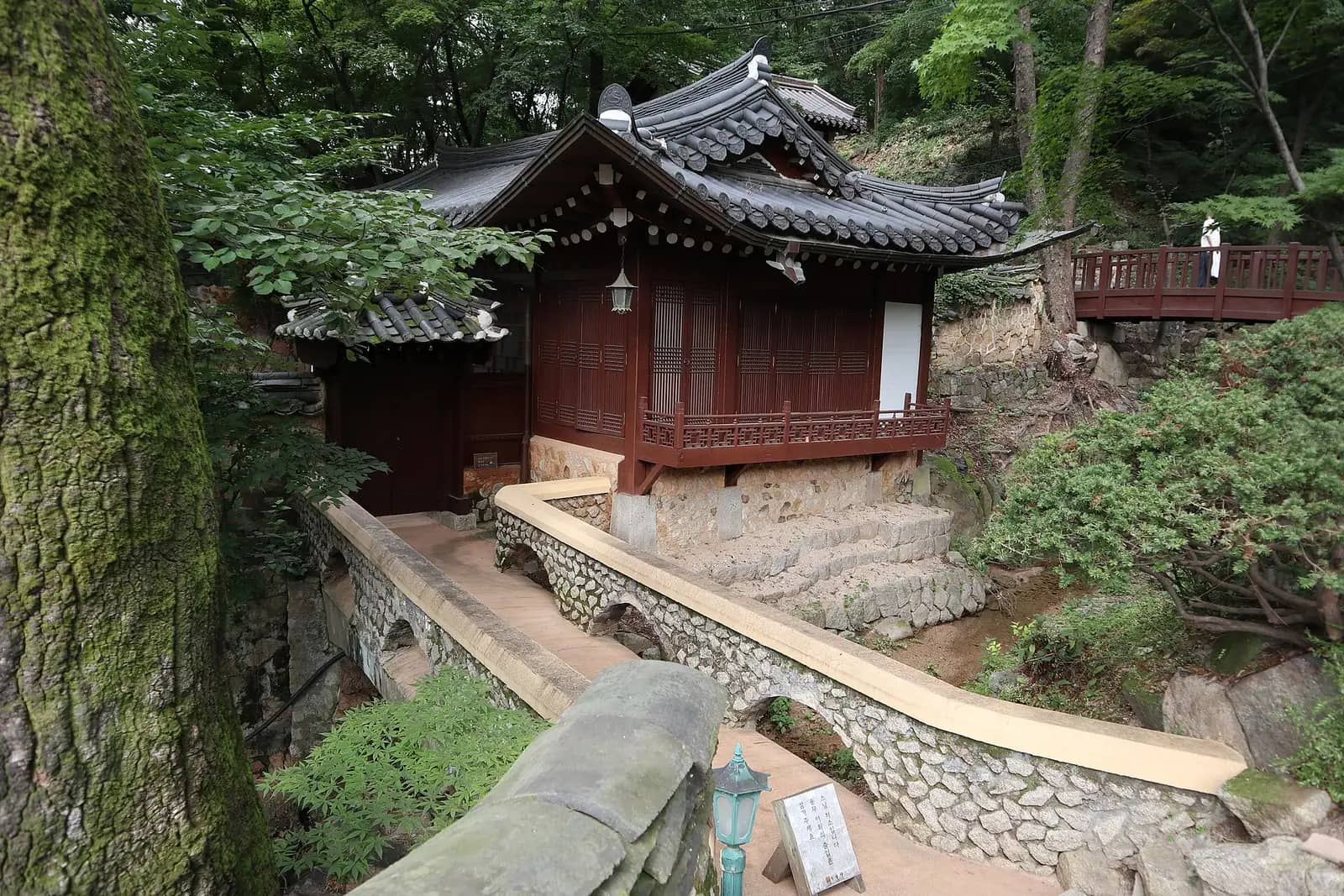 Dark wooden hall with tiled roof on a wooded slope at Gilsangsa temple, Seongbuk-dong