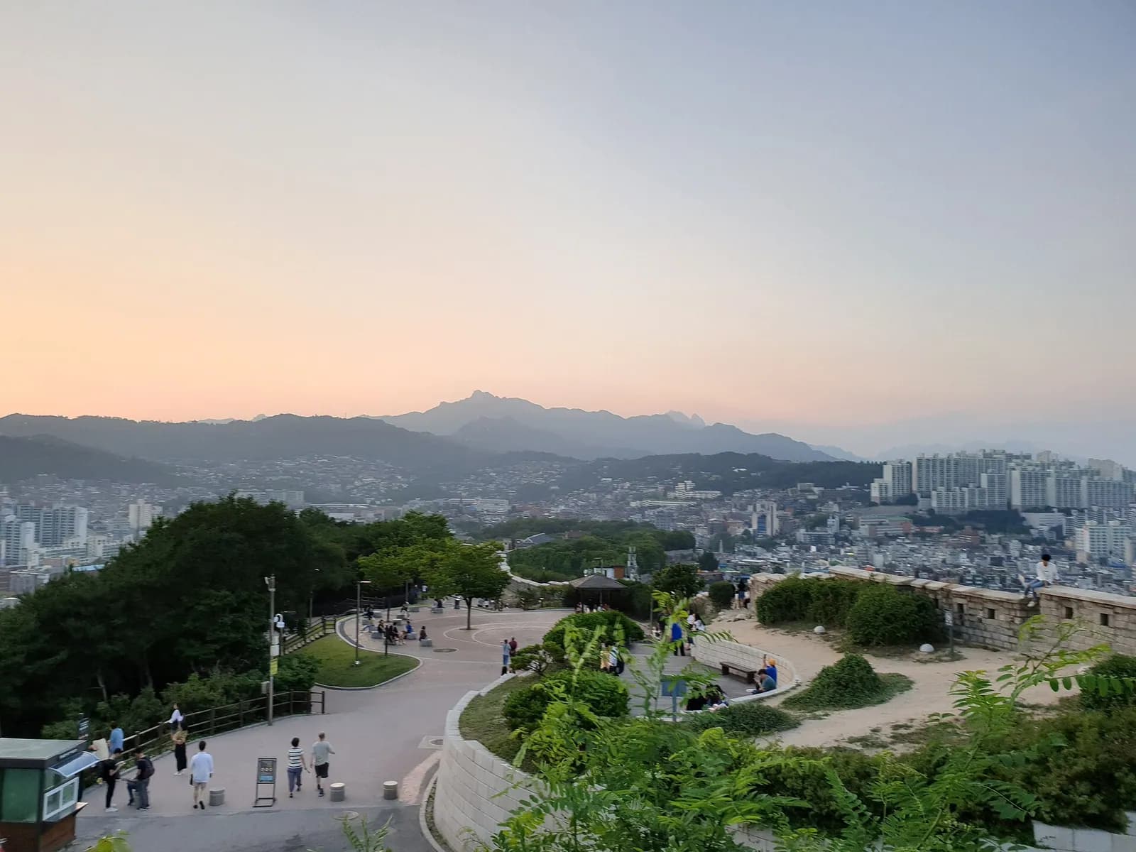 Naksan Park paths and Seoul City Wall at dusk with mountains on the horizon