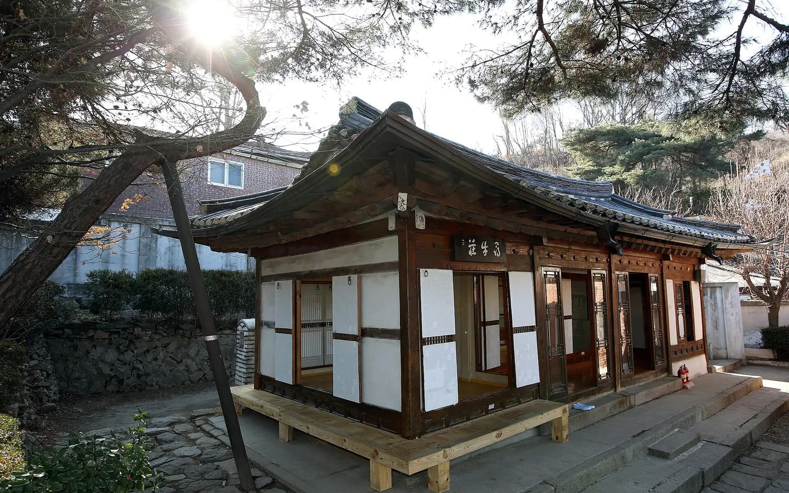 Small hanok house Simujang with paper doors under pine trees in Seongbuk-dong