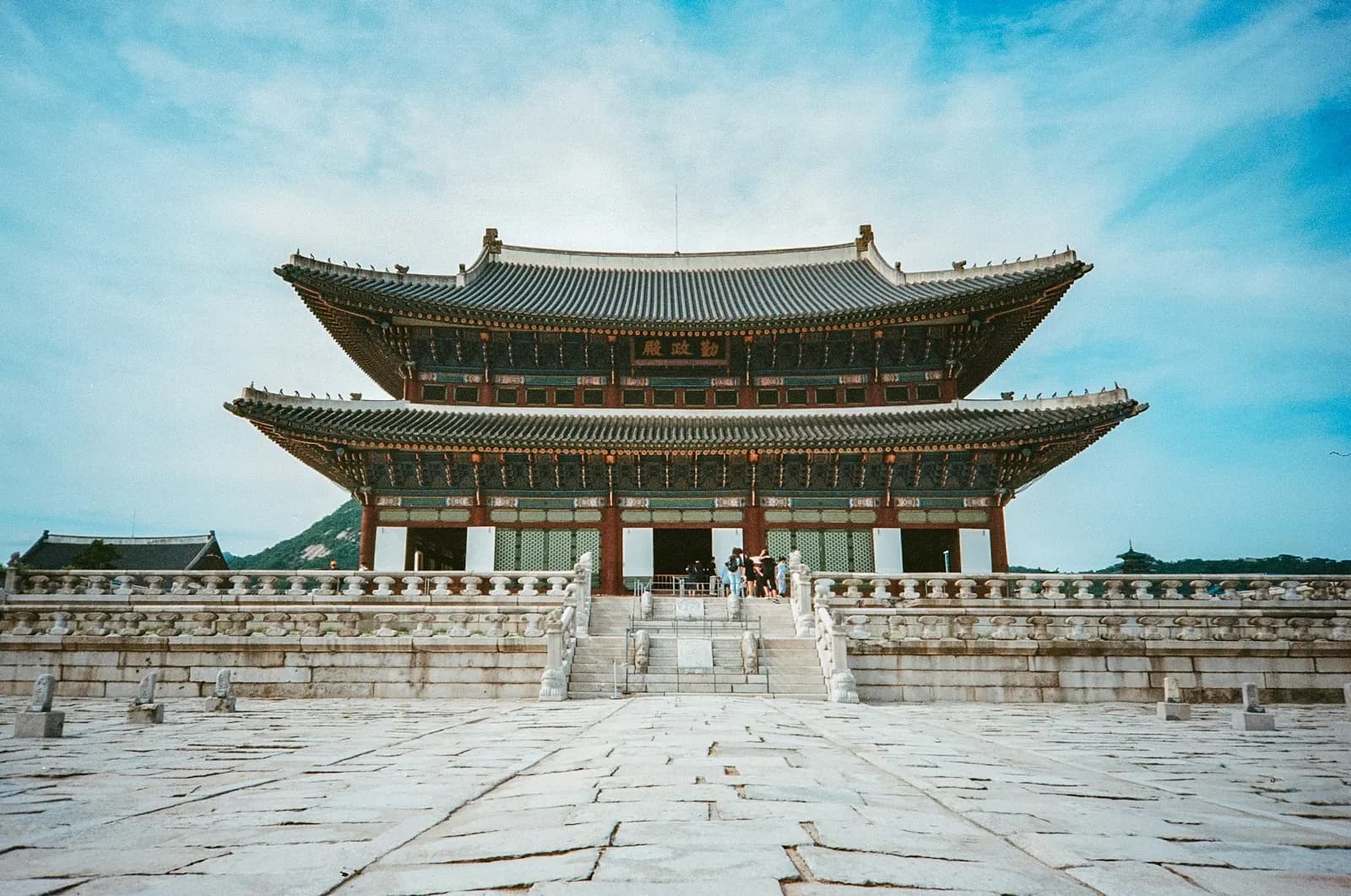 Geunjeongjeon Hall at Gyeongbokgung Palace across its stone courtyard under a blue sky