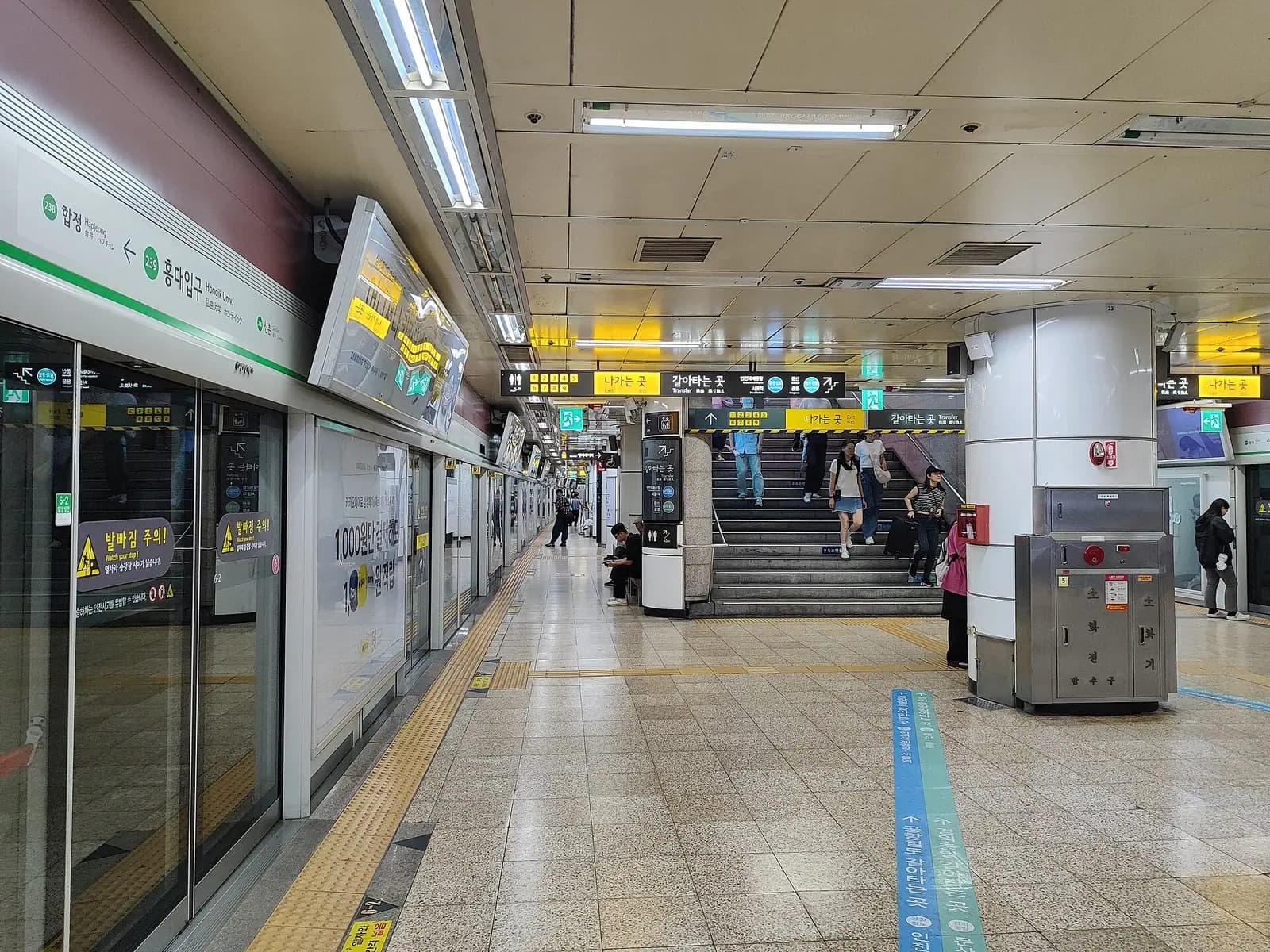 Line 2 platform at Hongik University Station in Seoul with platform screen doors and overhead direction signs